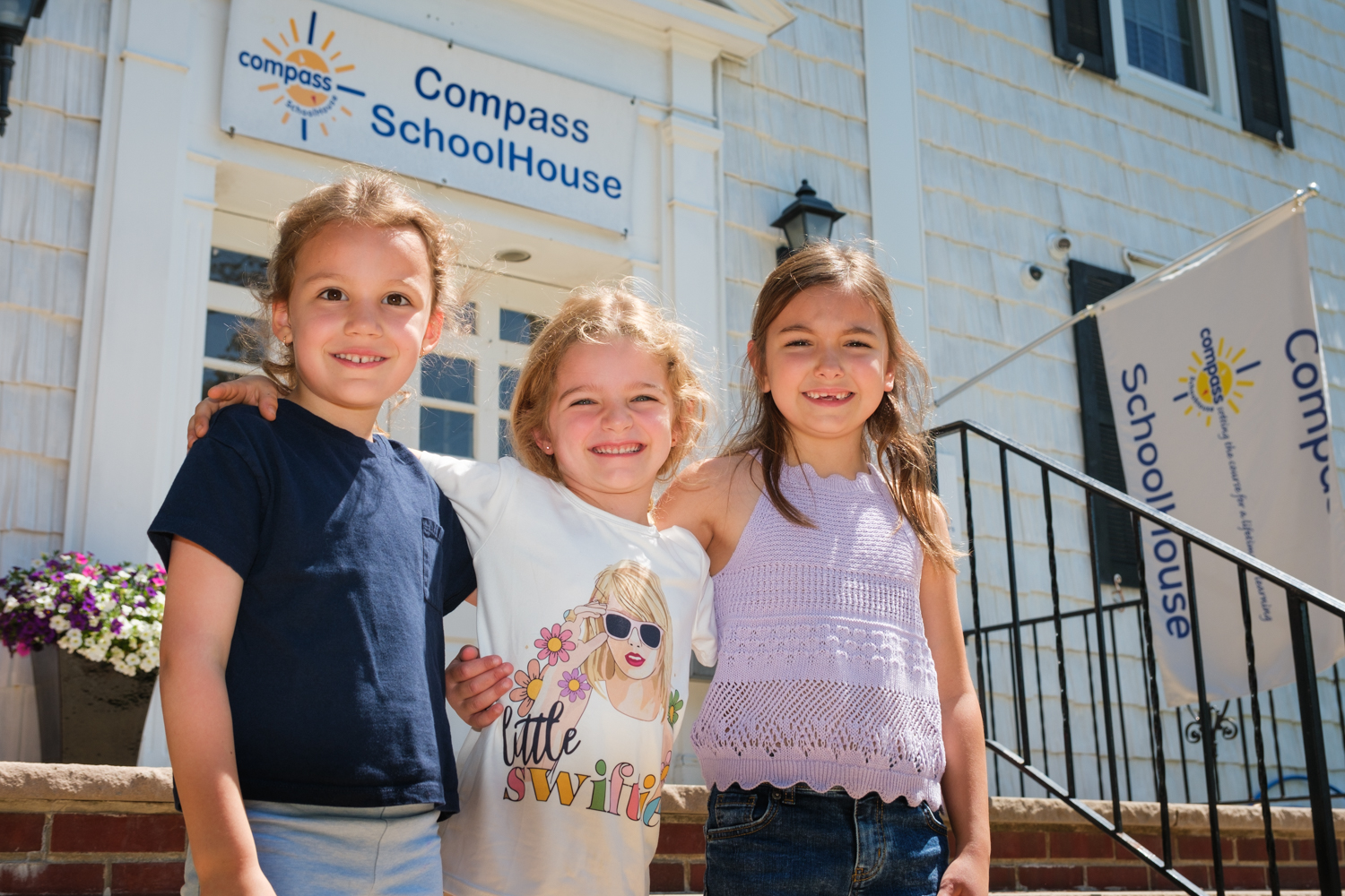 Three smiling children standing outside Compass SchoolHouse. Three smiling children standing outside Compass SchoolHouse.